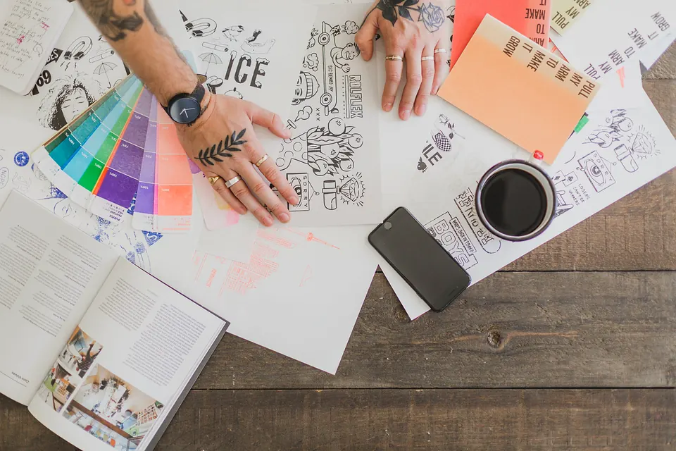 A designer's desk covered in sketches, colour swatches and pens, seen from above