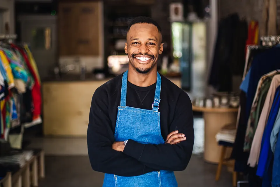 A shop owner in a denim apron standing in his clothing store
