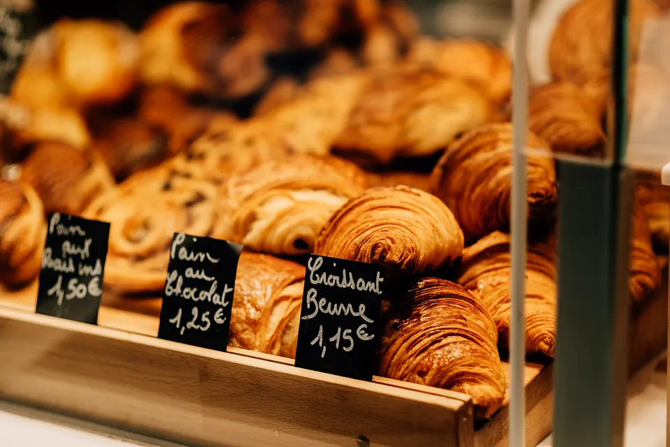 A tray of croissants with chalk price tags in a bakery window