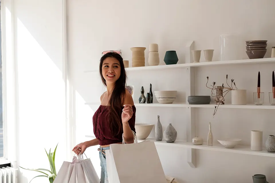 A shopper with paper bags smiling in a ceramics shop