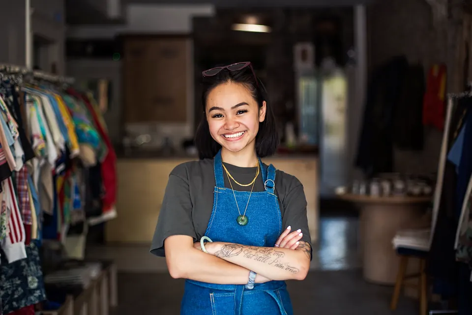 A shop owner in a denim apron smiling in her clothing store