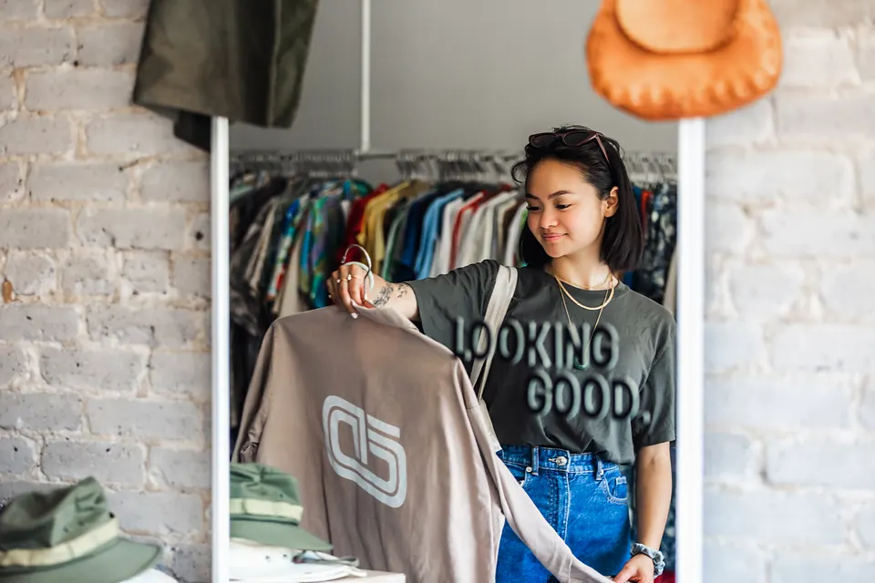 A shopper holding up a sweatshirt in a vintage clothing shop