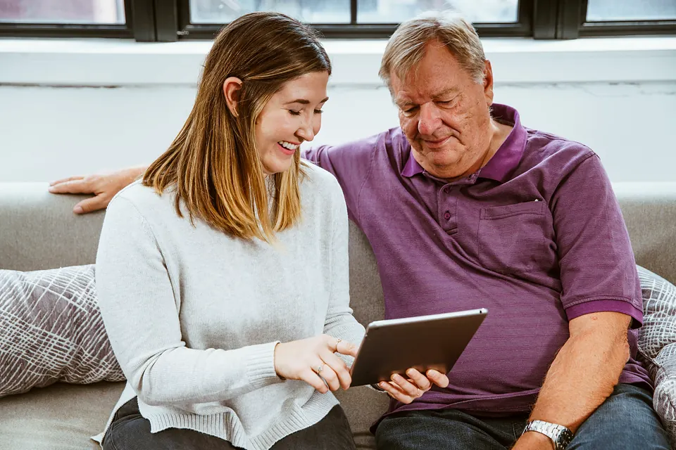 A younger woman showing an older man something on a tablet