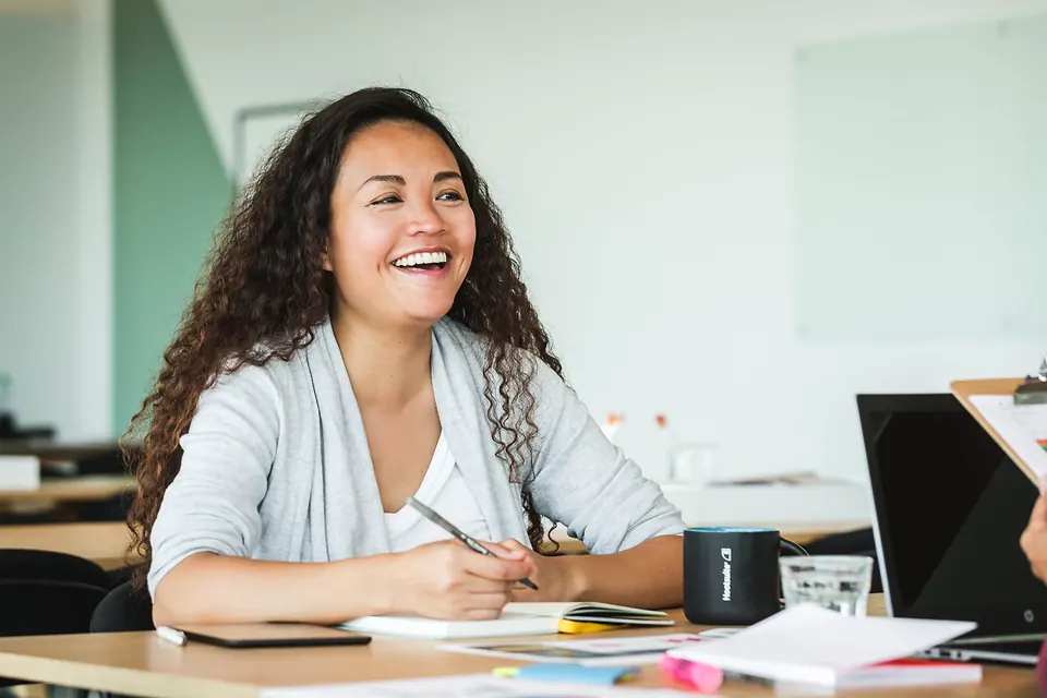 A woman laughing at her desk